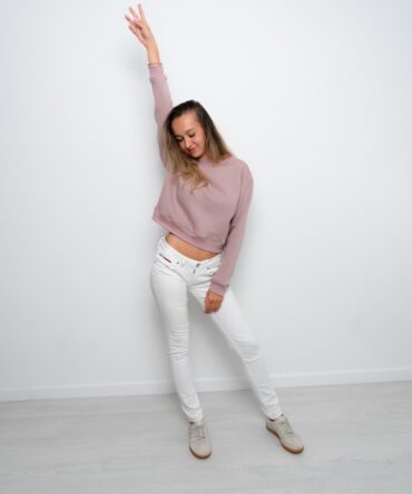 Modelka w krótkiej bluzie crop top w kolorze róż nude, uszytej z bawełny premium z misiowym wnętrzem. Dopasowany fason podkreśla talię – produkt Kadora Studio.